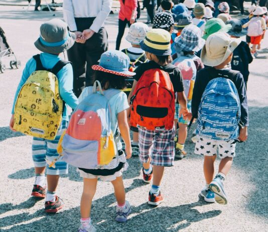 어린이보호구역 안전시설 확충에 289억 원 신속 투입 group of people wearing white and orange backpacks walking on gray concrete pavement during daytime