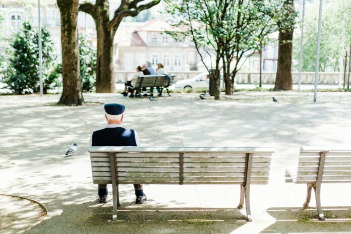 Photo by Bruno Martins person sitting on beige street bench near trees