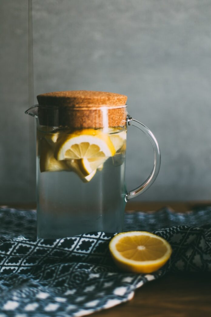 Photo by Daiga Ellaby clear glass pitcher filled with sliced lemons on black and white table runner