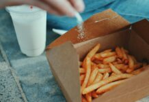 저염식 다이어트: 나트륨 섭취를 줄이는 방법과 효과 person sprinkling salt in fries