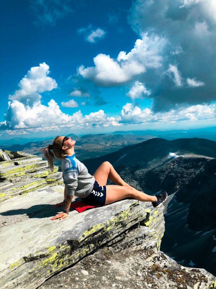 Photo by Charlotte Karlsen woman sitting on peak of mountain