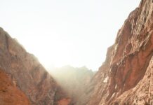 건강과 다이어트를 위한 야외 활동 a man walking down a dirt road next to a mountain