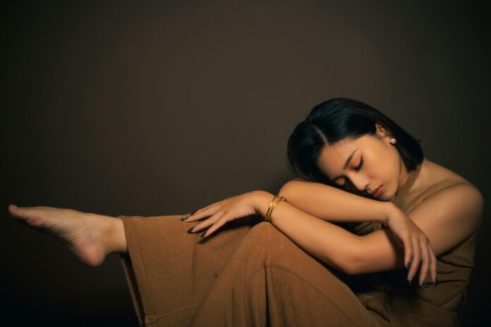 Photo by Chris Yang a woman sitting on the ground with her arms crossed