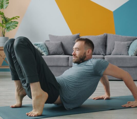 슬림 레그 가이드: 부기 없는 매끈한 다리 라인을 위한 하체 순환 Man doing yoga on a mat in a living room.