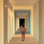 ‘마이크로 운동’이 바꾸는 우리의 하루, 짧고 자주 움직이기가 건강 열쇠 Woman walks down a sunlit colonnade hallway.